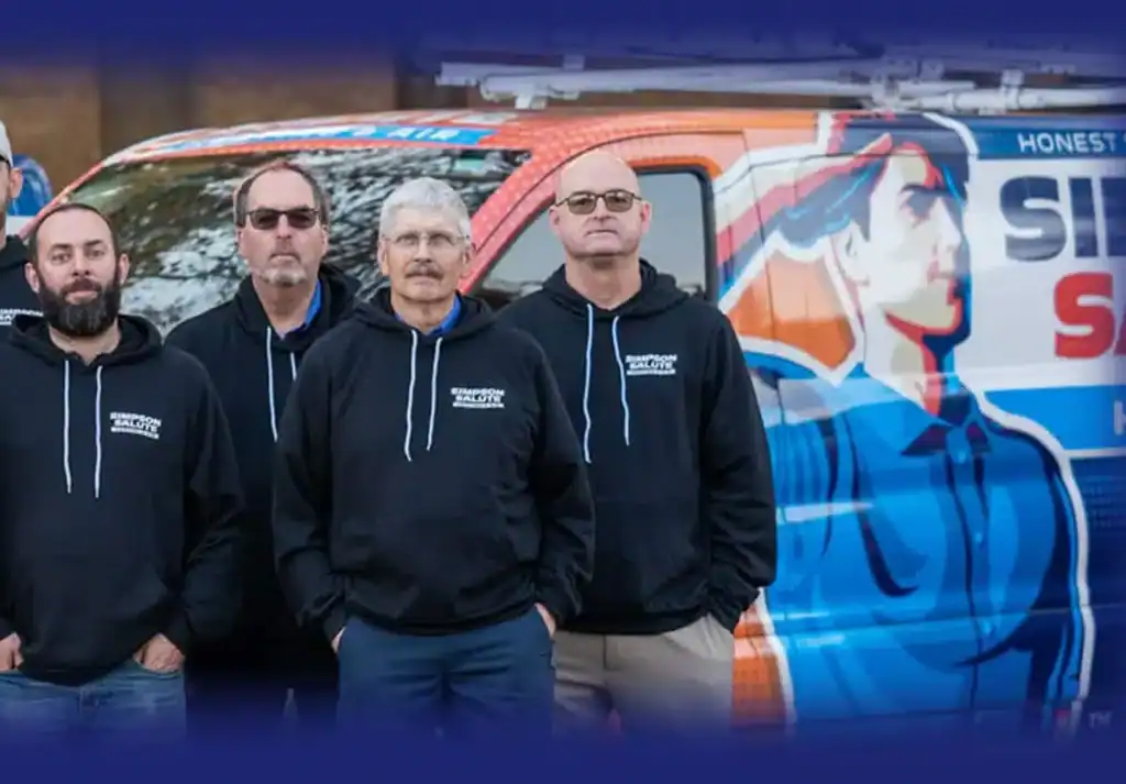 Four men in black hoodies stand in front of a brightly colored service van with graphics and text on its side.