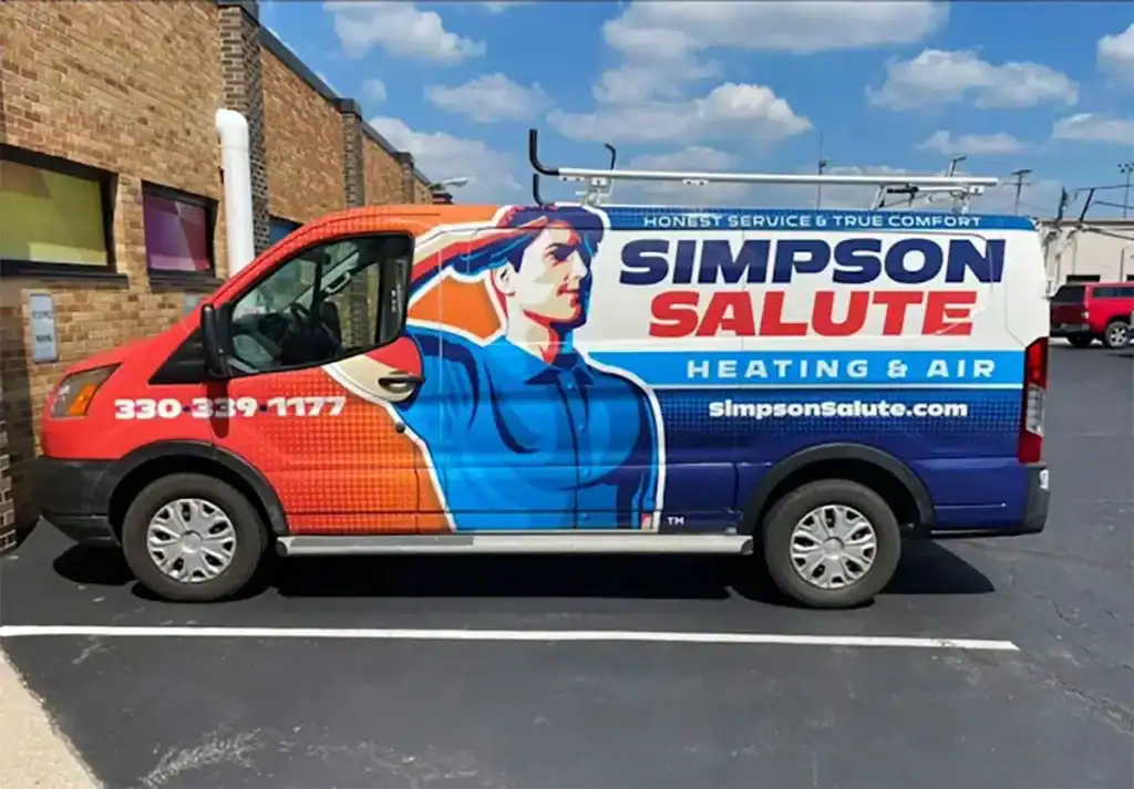 A van with a colorful wrap advertising Simpson Salute Heating & Air is parked next to a brick building. The design features a worker illustration and contact information on the side.